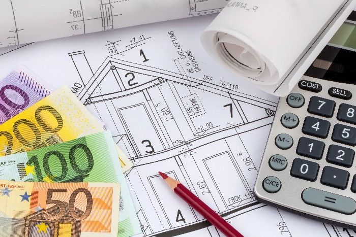 Bauplan eines Hauses mit Euro-Banknoten und einem Taschenrechner